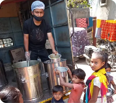 Volunteers serving cooked meals to school children during a community nutrition program 